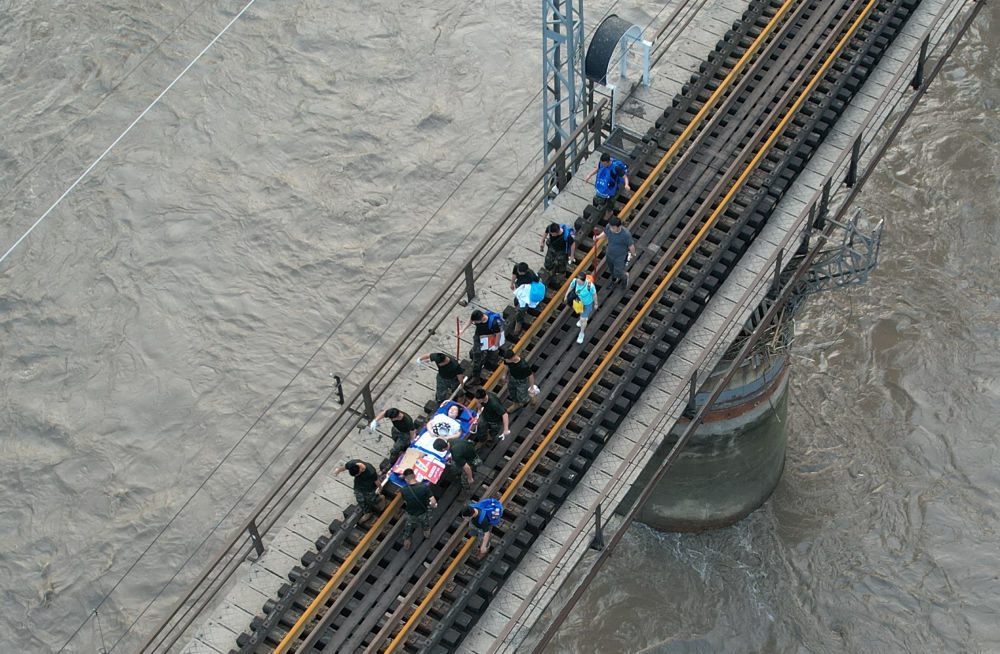 8月2日，受困列车旅客在救援人员帮助下徒步赶往转运客车（无人机照片）。新华社记者 张晨霖 摄