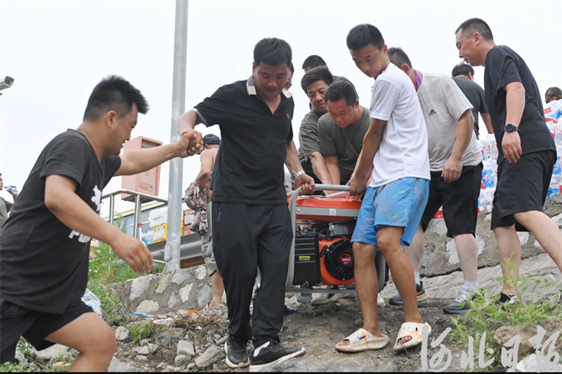 8月3日，涞水县自然资源和规划局党员服务队和三坡镇当地村民一起搬运发电机。