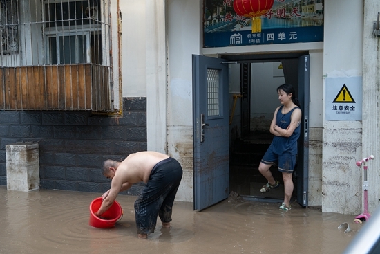 7月31日，北京，门头沟区桥东街小区，一层房屋进水的住户，在水退下后清理房屋。视觉中国供图