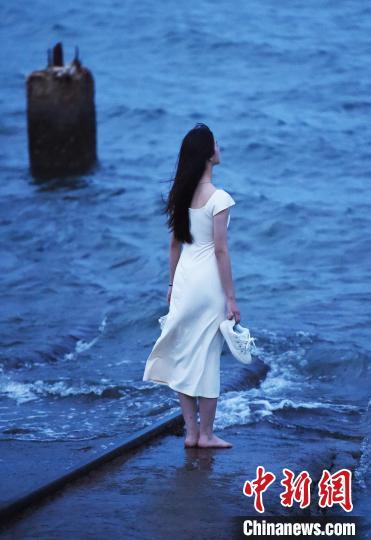 游客模仿动漫角色的动作，双手提鞋沿着铁轨前行。曲正扬 摄