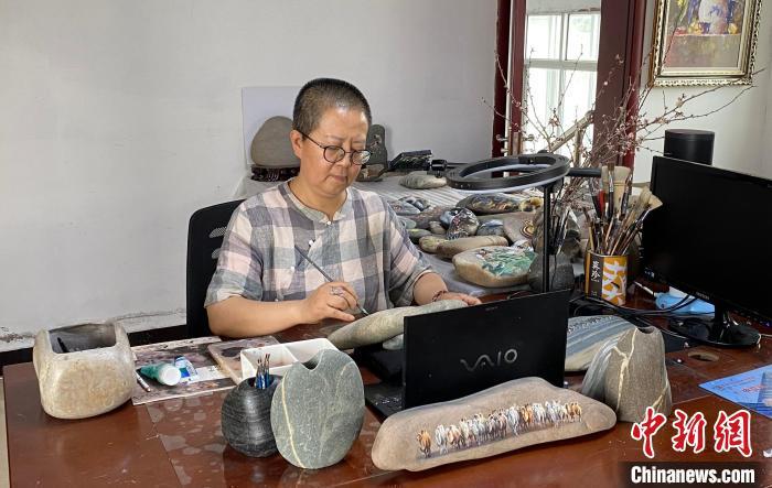 图为马玉兰正在工作室里绘制黄河石画 高莹 摄