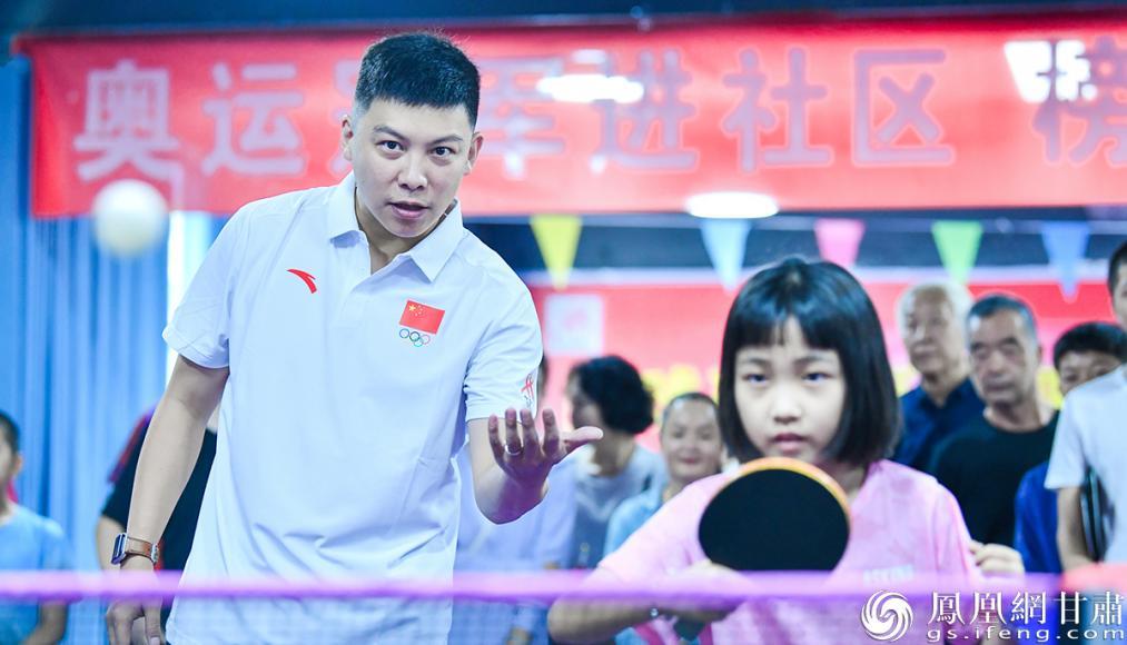 奥运冠军、江苏省乒乓球队总教练陈玘（前左）走进甘肃省武威市凉州区大新社区，现场指导乒乓小将。