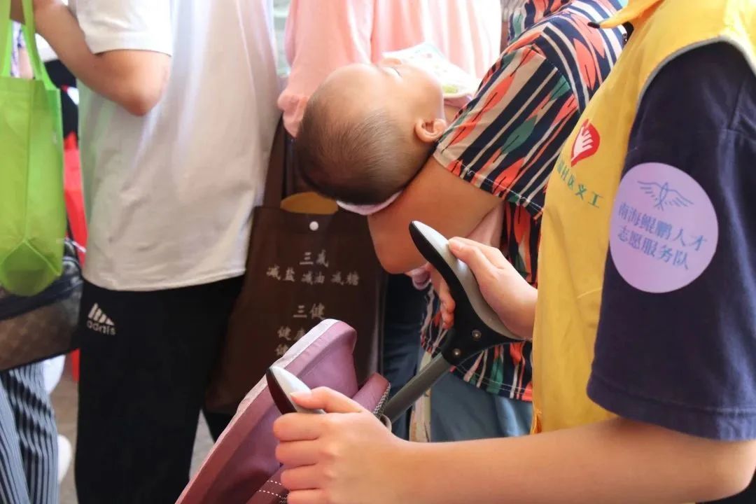 一位市民在排队过程中,因怀抱着婴儿、不方便推婴儿车,南海鲲鹏人才志愿服务队的志愿者陪同在其身旁,全程帮忙推车
