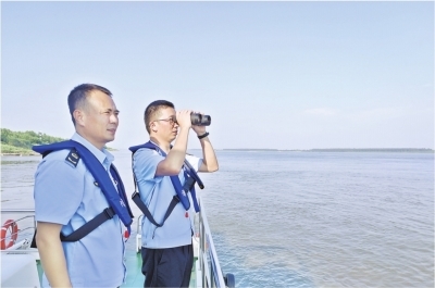 渔政执法人员用望远镜察看长江江豚出没。