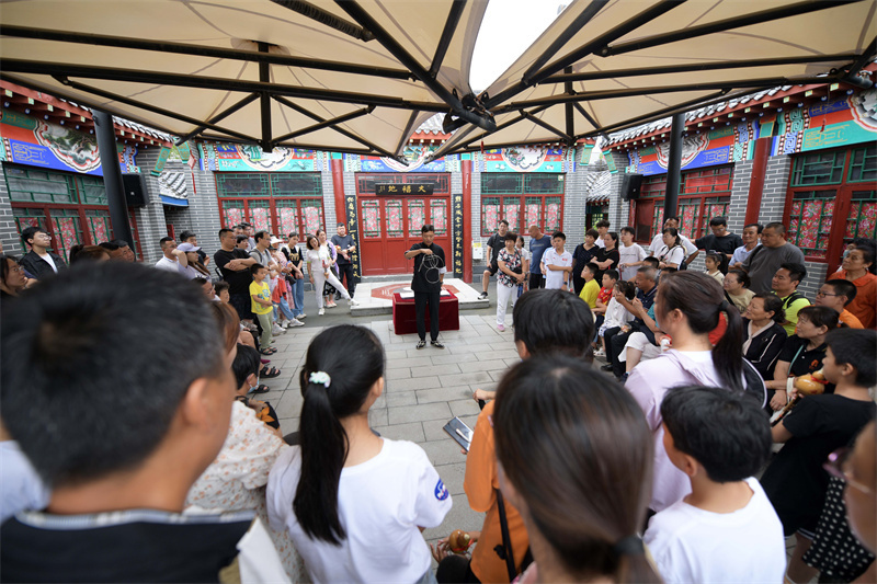 8月12日，在河北省沧州市吴桥杂技大世界景区江湖文化城，游客们观看杂技艺人表演传统杂技节目。