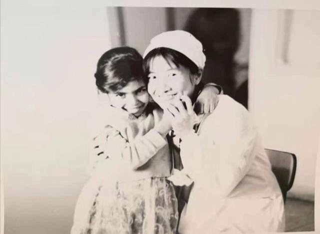 中国援阿医疗队、中南大学湘雅医院妇产科医生张友明（右）身穿白大褂，笑靥如花地搂着一个大眼睛的阿尔及利亚小姑娘。