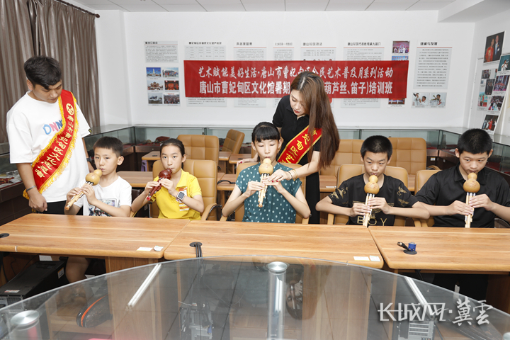 文艺志愿者在教授公益艺术培训课的小学员们葫芦丝演奏。