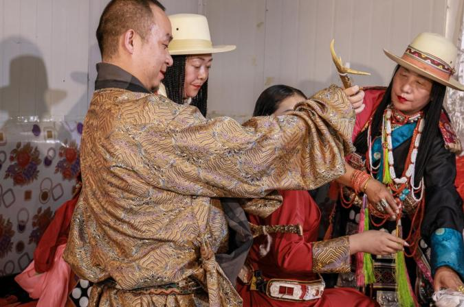 新娘的哥哥用干鹿角分发并为她梳好脑后的小辫子