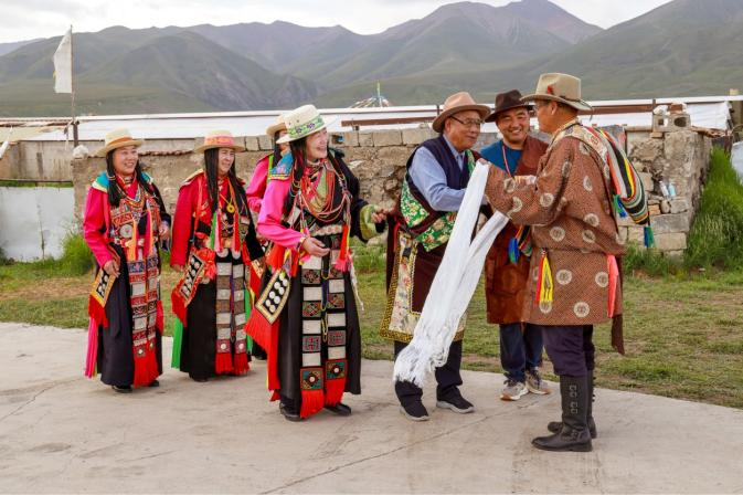 图为媒人到女方家提亲,女方家人在门口盛装迎接。