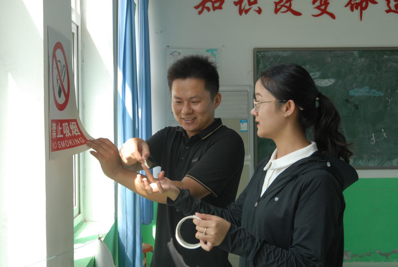 9月7日,山东省青岛市即墨区田横岛小学女教师刘辉辉(右)和爱人本学校老师董立俊在学校张贴警示标志。女教师刘辉辉在田横岛小学找到了自己的真爱。