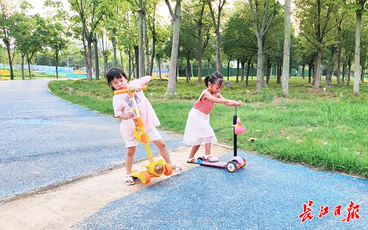 小朋友在公园内玩滑板车,过沟坎需要停下来.记者孙笑天 摄