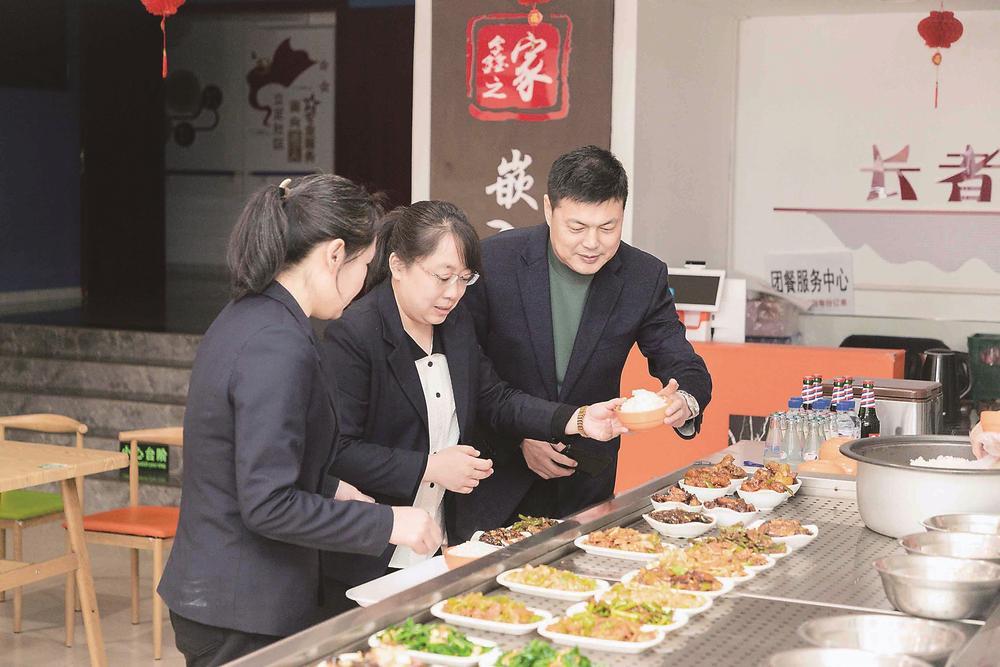 负责运营惠民嘉苑社区敬老餐厅的第三方机构工作人员正在检查饭菜质量。 （长春市惠民嘉苑社区供图）
