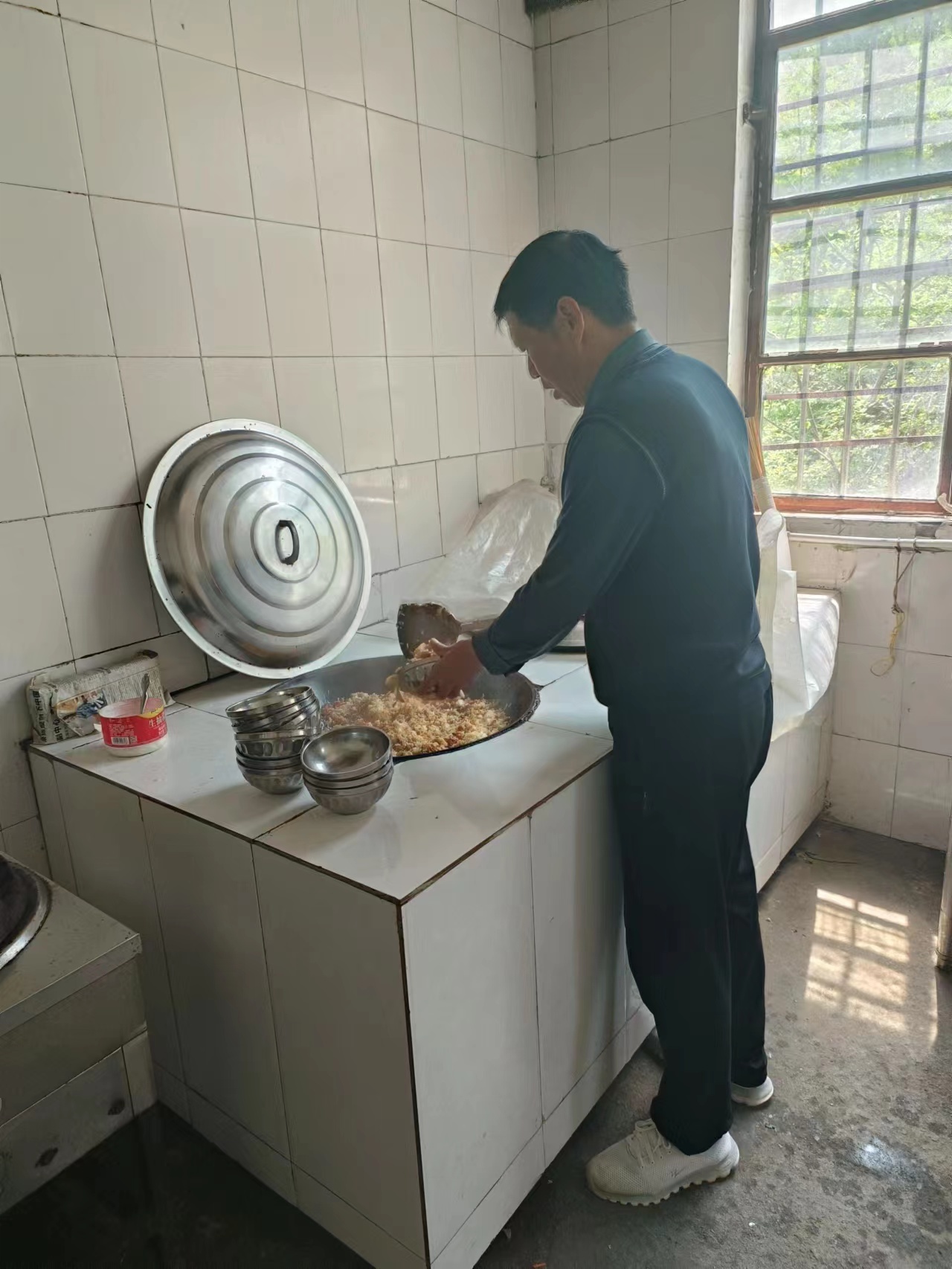 石龙伟在学校厨房为孩子们做饭。