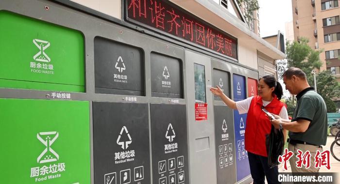 图为在齐河县永嘉社区的智能垃圾分类驿站，工作人员正在对前来投递垃圾的民众进行垃圾分类指导。齐河县委宣传部 供图