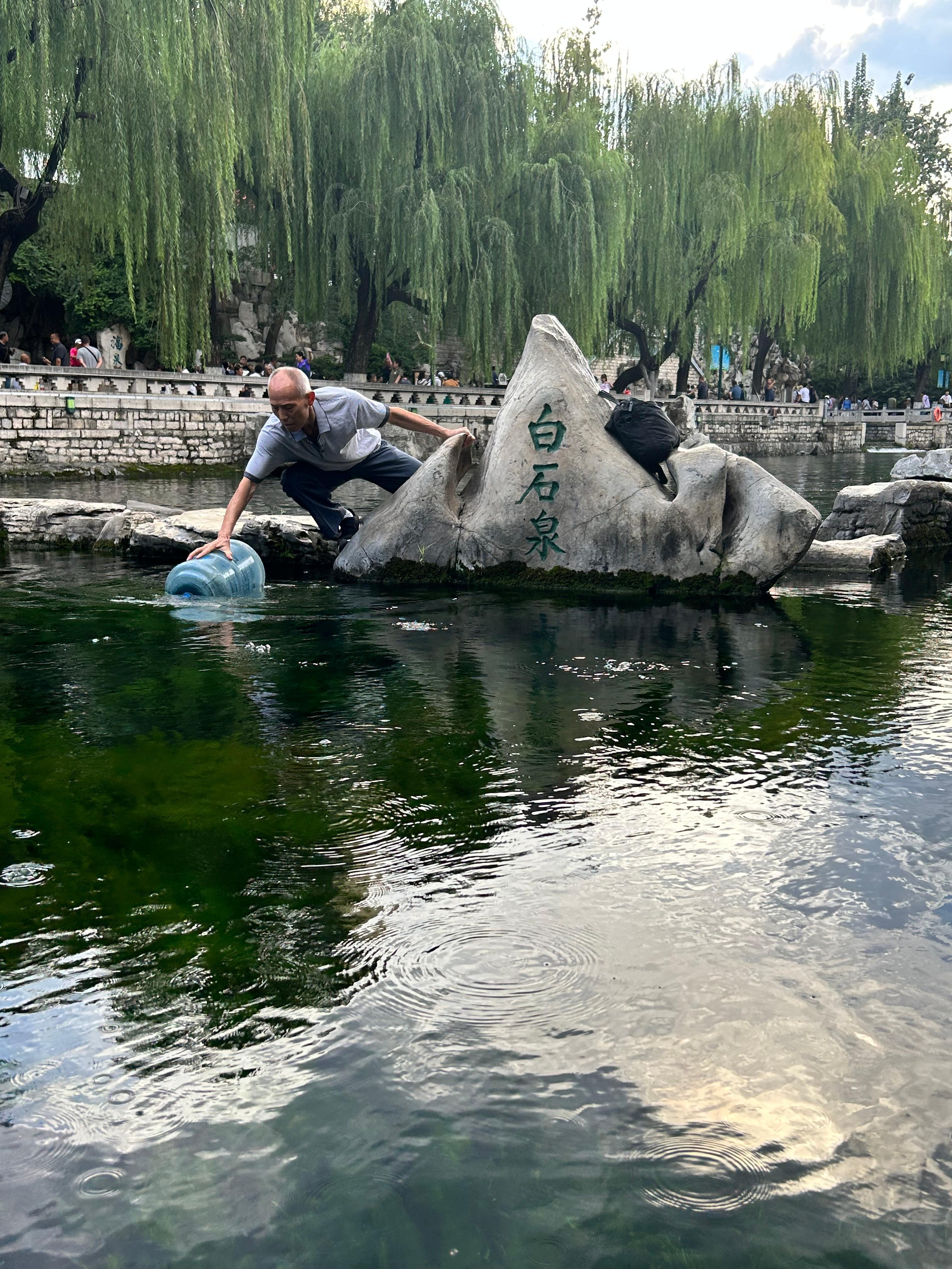 一位大爷在白石泉灌泉水。