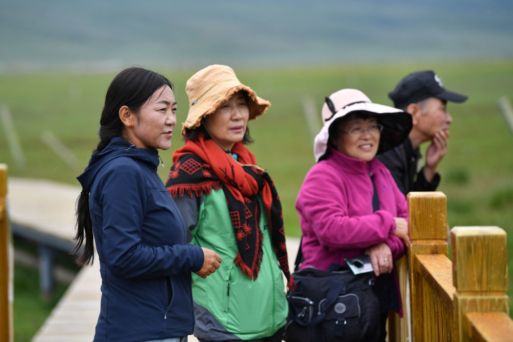 甘肃尕海则岔国家级自然保护区管护中心尕海保护站站长香毛吉（左一）向游客介绍保护区的野生动植物情况　新华社记者　陈斌　摄