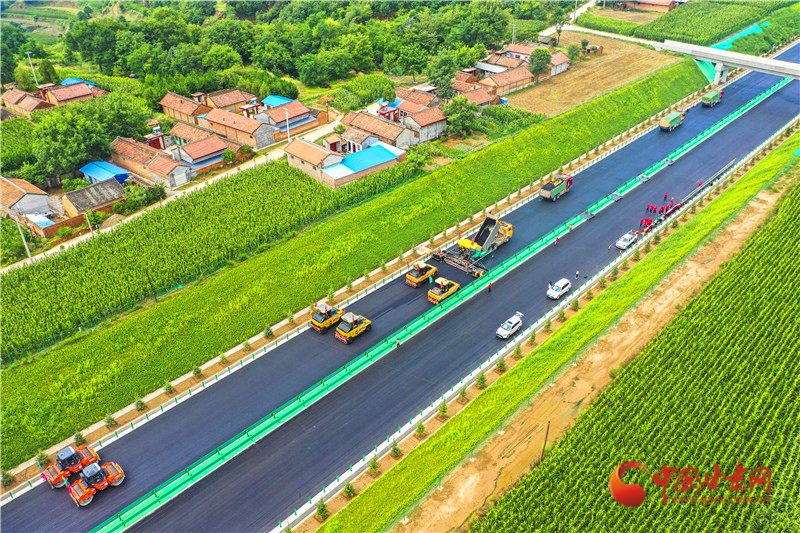 正在进行路面面层碾压的挖方路段