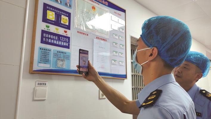 县市监局执法人员在进行监督检查时，通过扫描“湘食安”二维码查看食品生产经营单位基本情况。高慧浈 摄