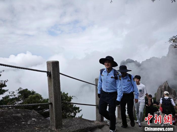 黄山莲花峰小哥们登上峰顶，维持游览秩序。赵美君 摄