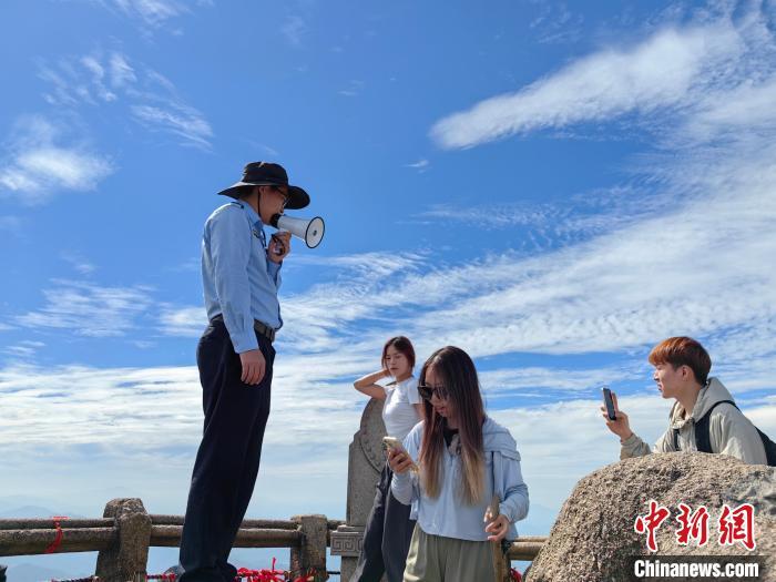 黄山莲花峰小哥在莲花峰顶手持喇叭喊话维持秩序。朱迎春 摄