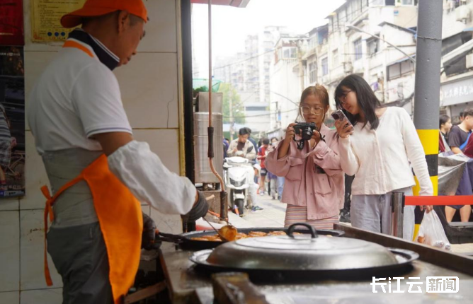 10月5日上午，山海关路，游客们用相机手机记录汽水包制作过程