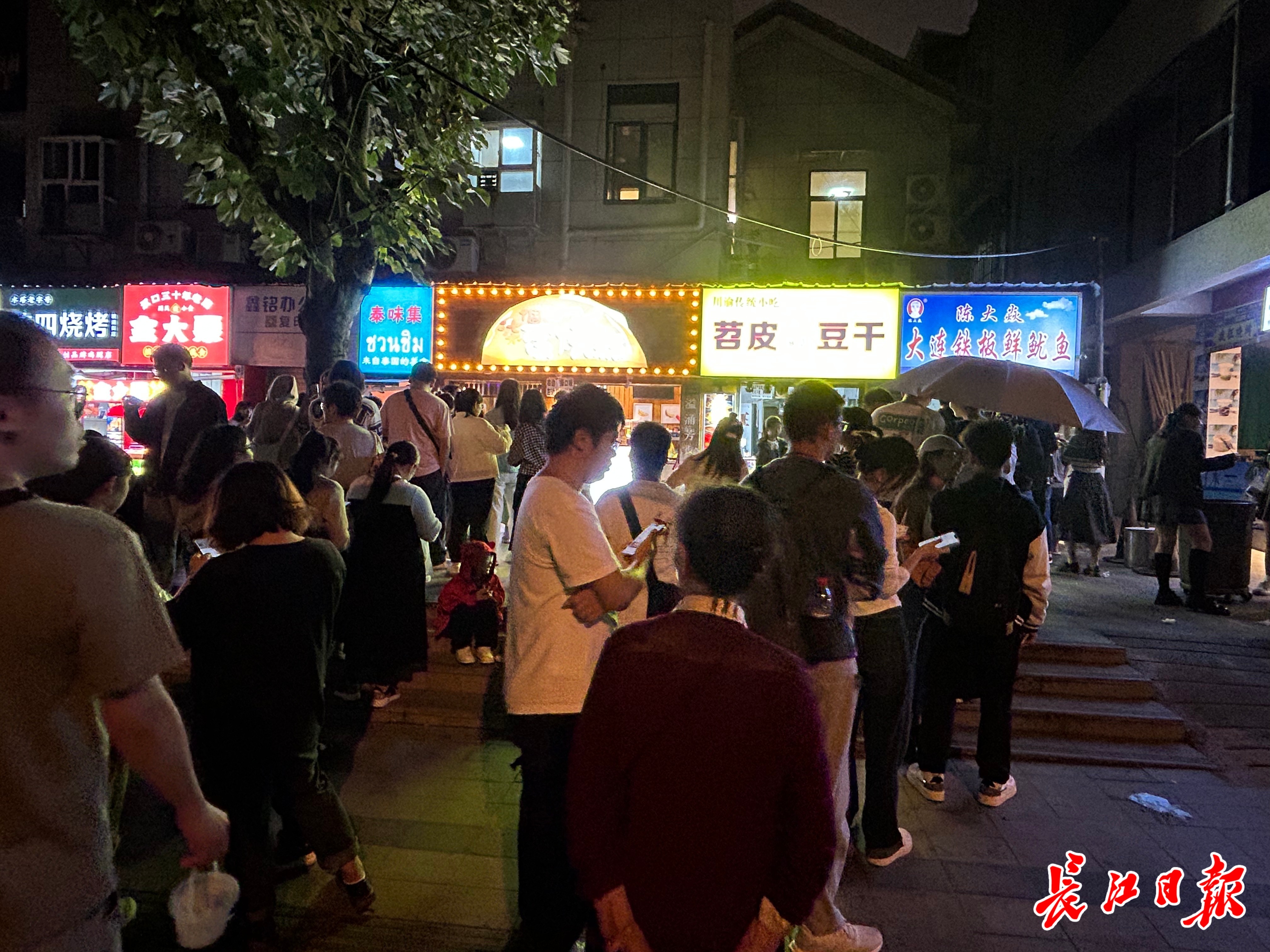 人们在雨中撑伞等待美食。见习记者李伊珏 摄