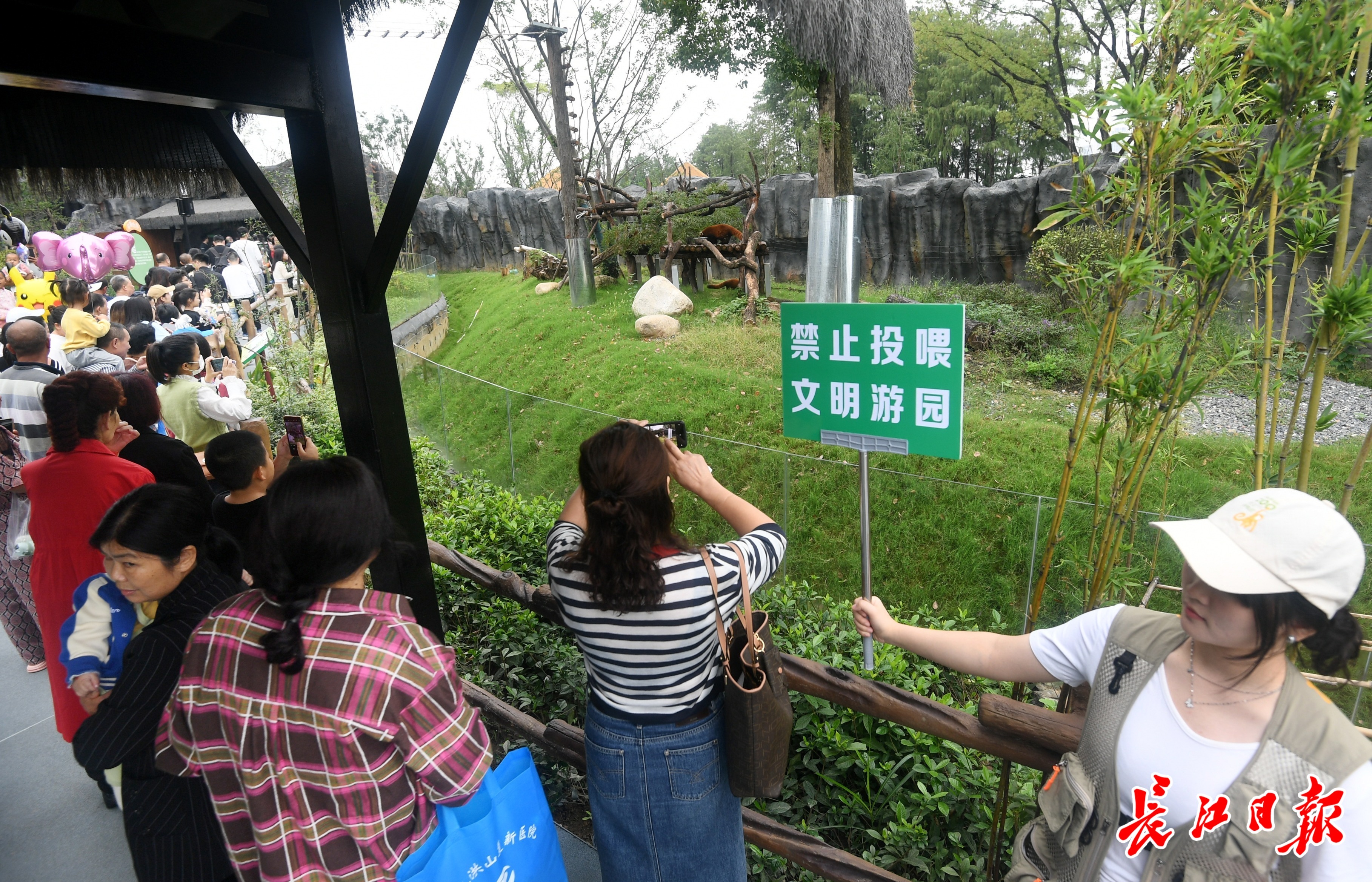 志愿者举牌提醒游客勿投喂动物。记者李子云 摄