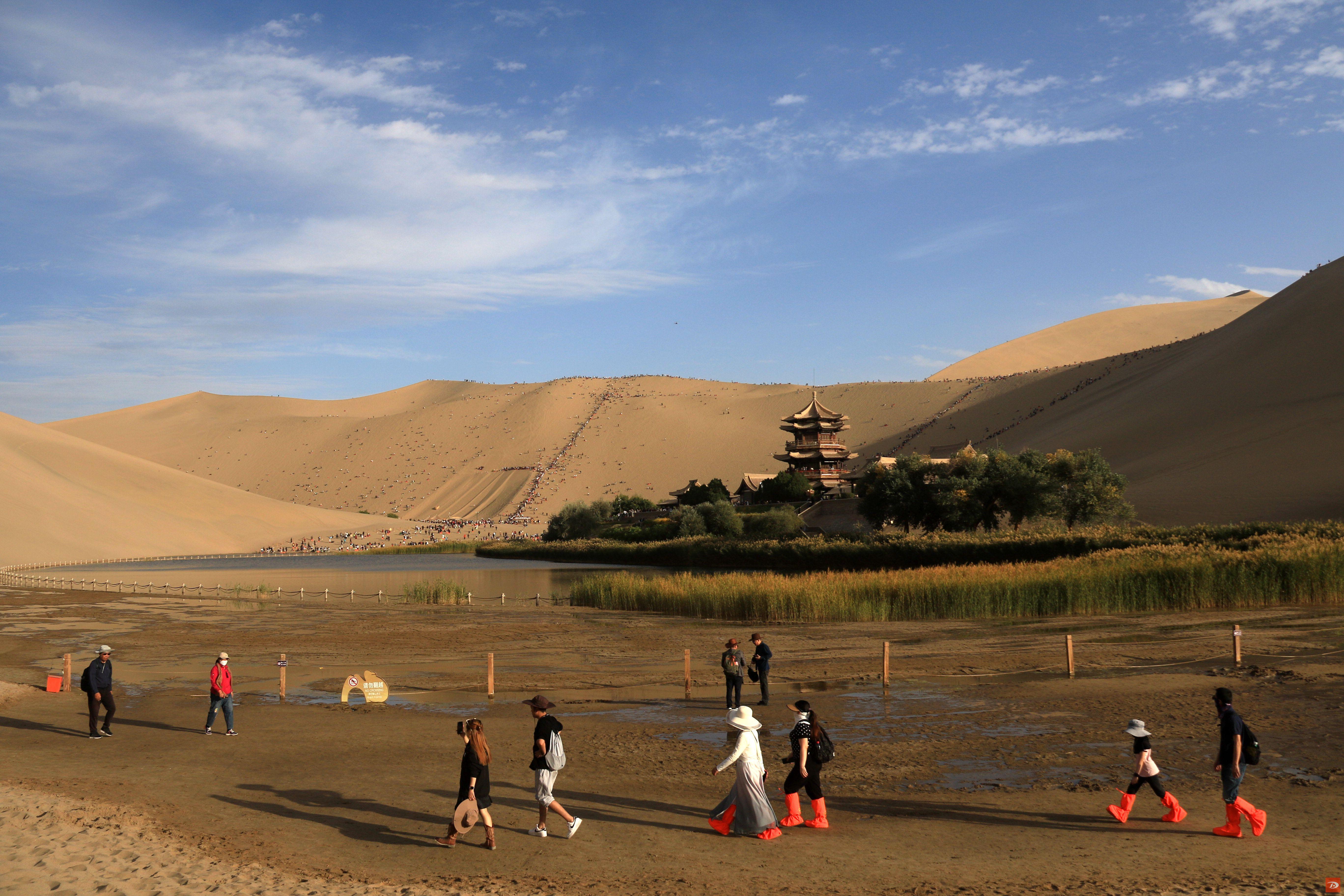 2023年10月3日，游客在甘肃省敦煌市鸣沙山月牙泉景区游览。