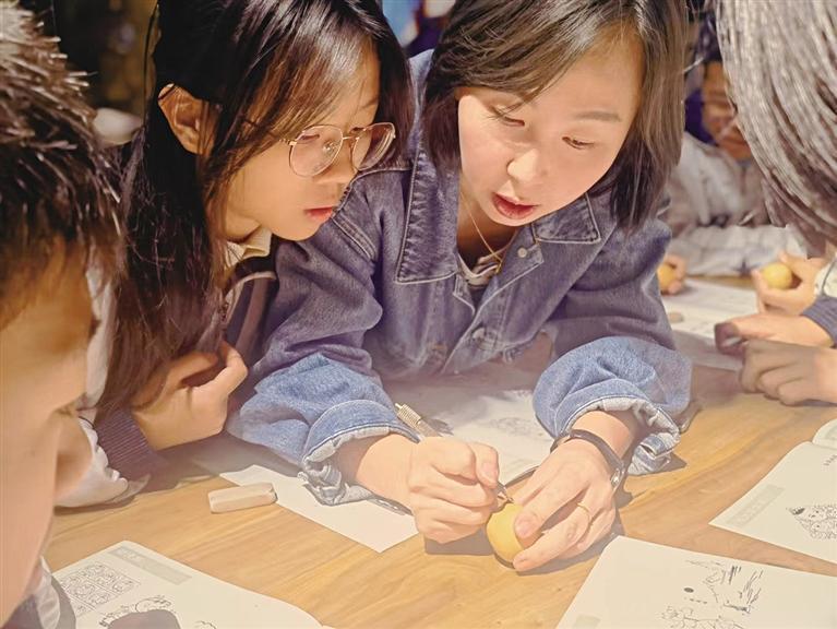 阮熙越正在教孩子们刻葫芦