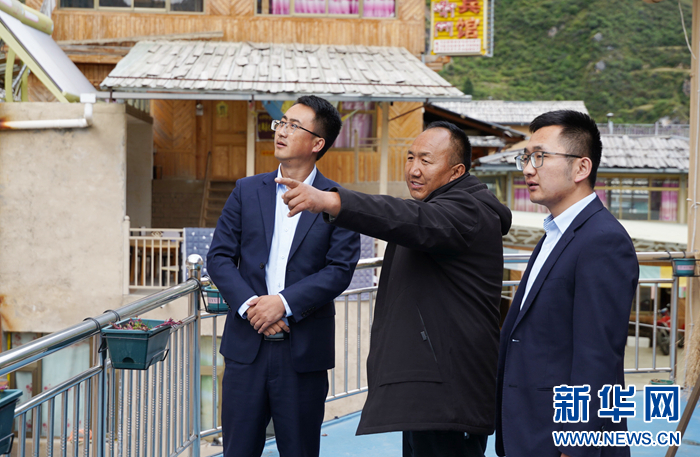 旺青闹加（中）向邮储银行工作人员介绍村子发展情况　新华网发（张铁梁　摄）