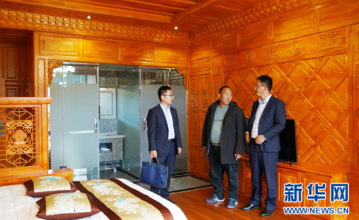 旺青闹加（中）带领邮储银行工作人员参观自家民宿 新华网发（王生元 摄）