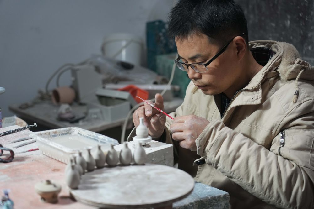↑2021年12月15日，来自安徽的王文化在制作微型陶瓷作品，他来景德镇已有十多年时间。