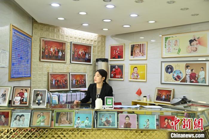 图为兰州照相馆工作人员展示介绍产品　李亚龙　摄