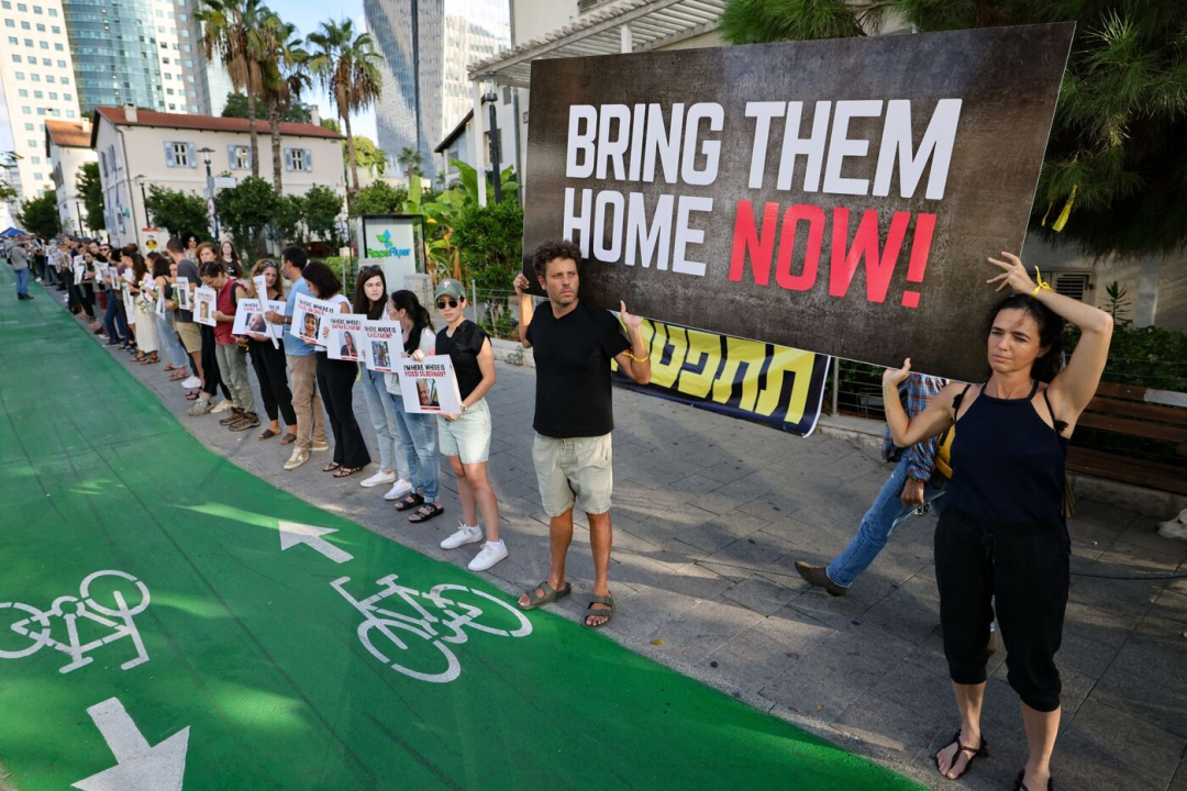 10月19日，以色列特拉维夫，人们举着写有失踪人员照片的标语牌，“现在就带他们回家！”图自彭博社报道配图