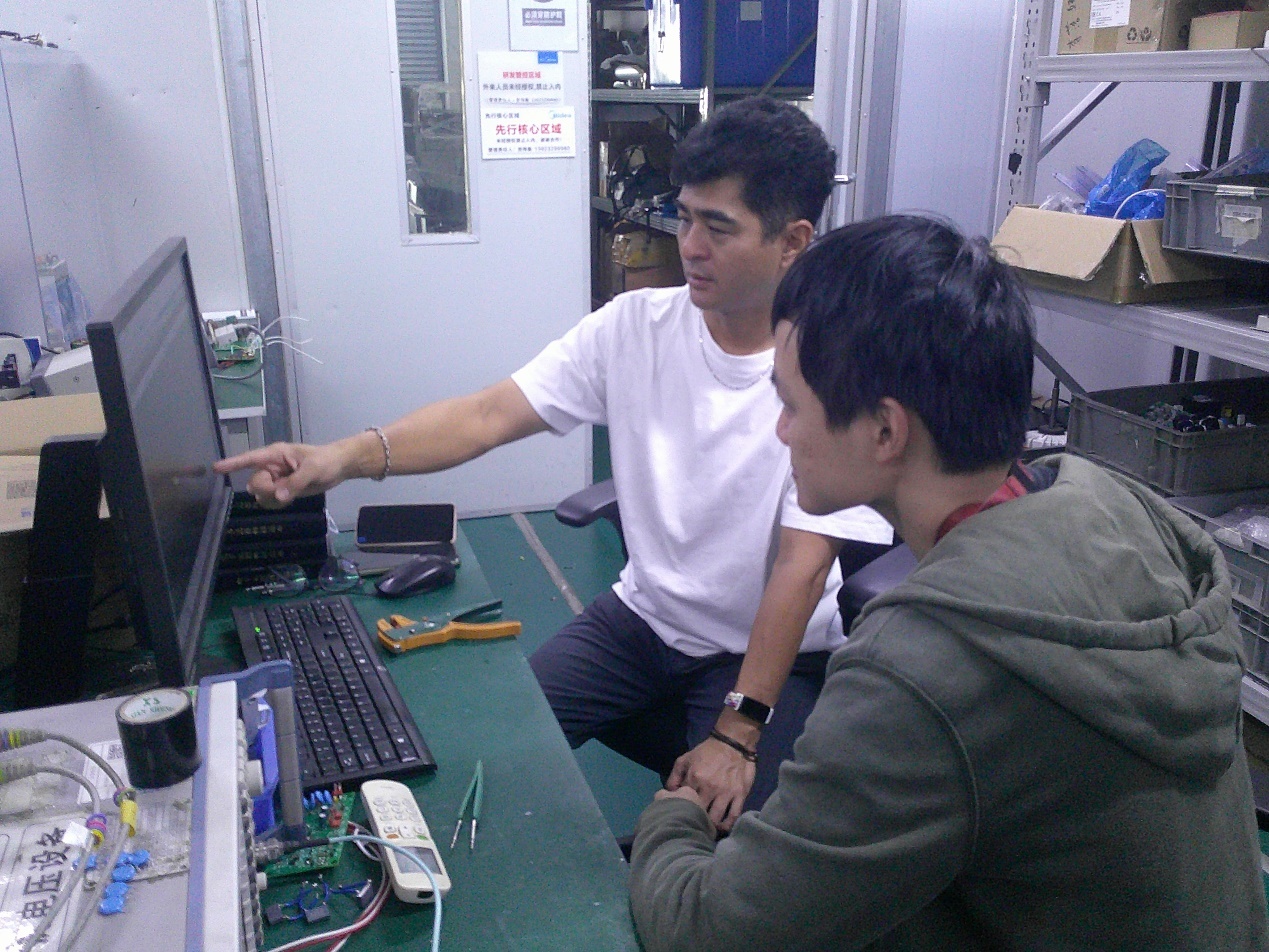 美的楼宇科技电力电子技术专家小仓健（左）与同事在讨论工作