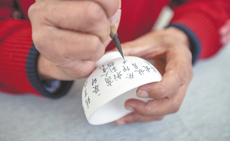 10月19日，景德镇市浮梁古县衙举办的茶瓷文化集市，书法匠人陈恒玉正在素坯上勾勒诗句。
