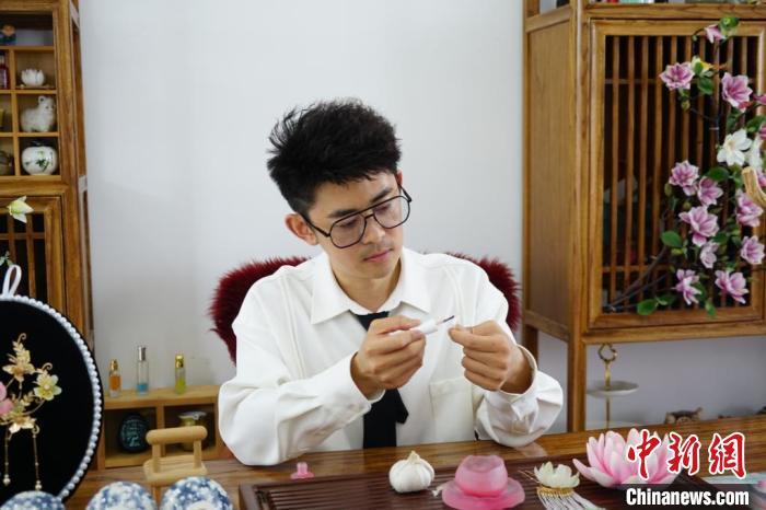 山东“90后”小伙王平用大蒜皮制作精美头饰，此刻正在用“指甲油”给大蒜皮上色。王采怡 摄