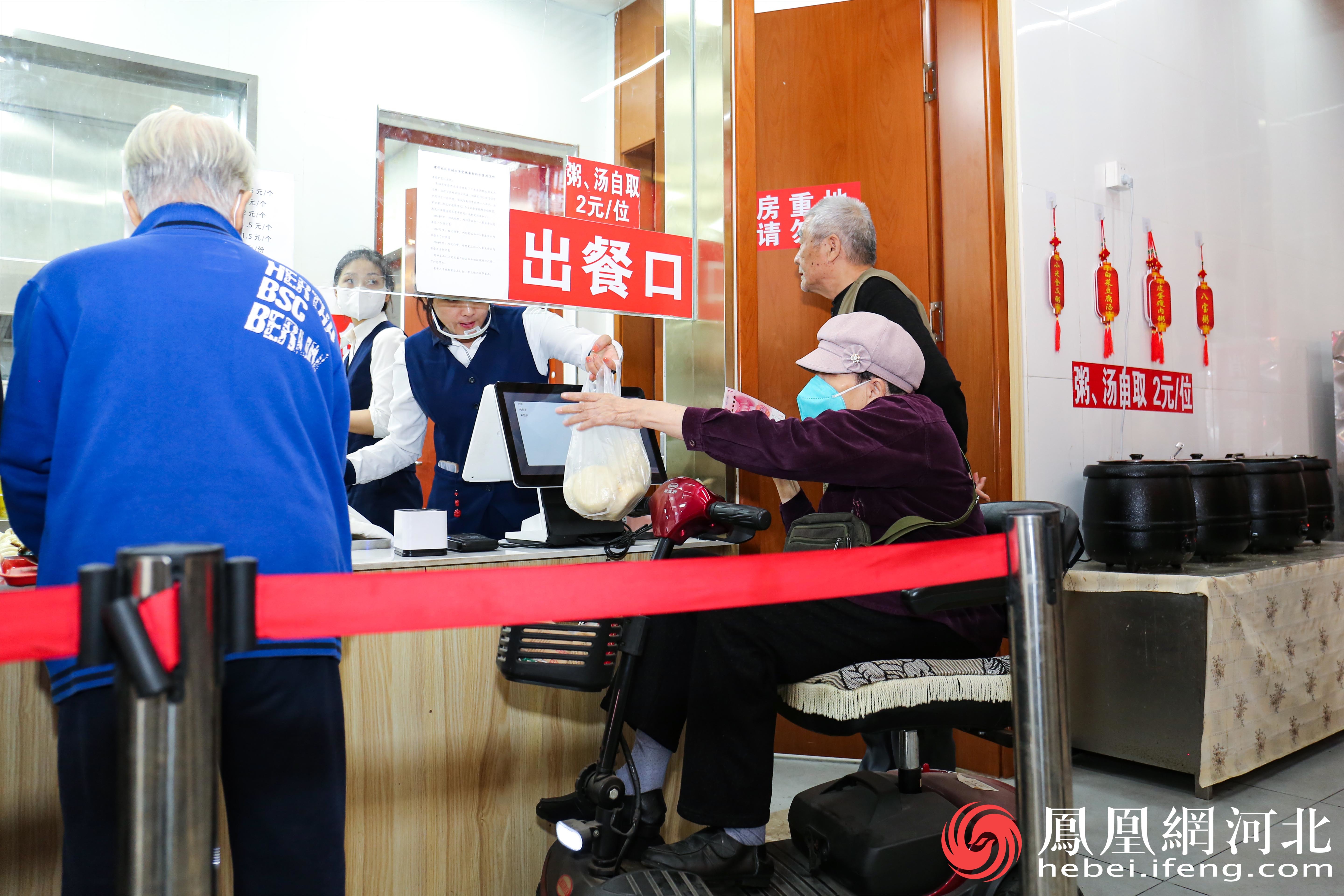 建明社区的老人们排队在窗口买饭