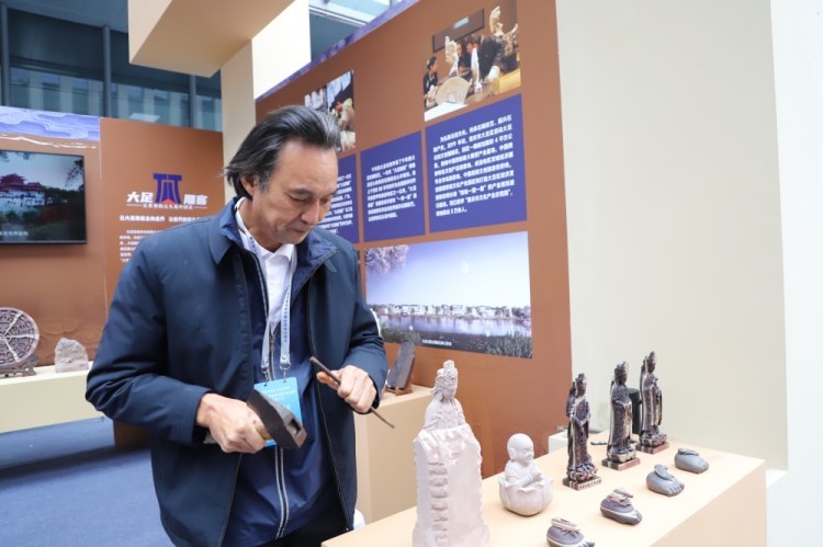 大足雕客形象代言人刘能风在参展现场展示精湛大足石雕技艺
