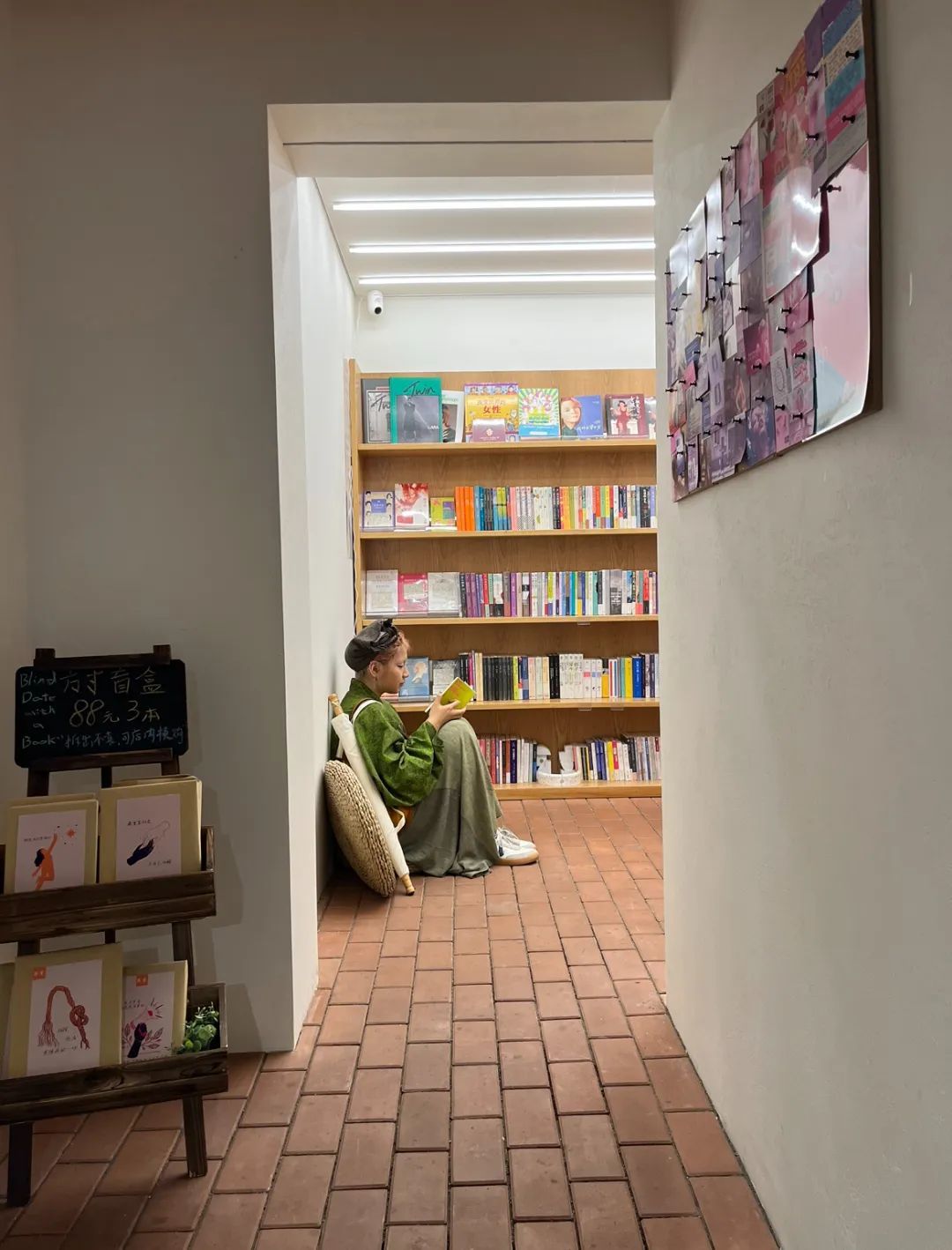 一位读者靠在书店的墙上认真阅读书籍。方寸书屋的门口是成都老牌面包店签名饼屋，两家原本毫不相干的店以这种独特的形式合二为一（图/阿祯 摄）