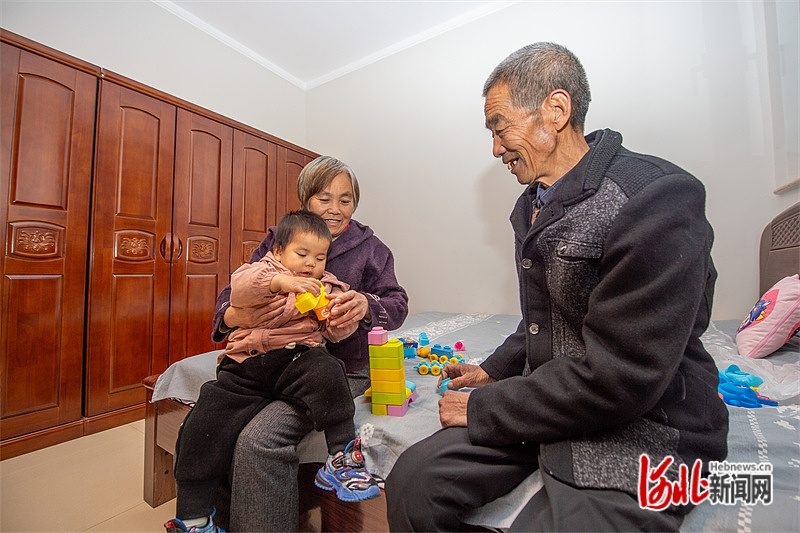 11月10日晚，在加固修缮后的房子里，涿州市万全庄村村民杨佩然（右一）老两口陪孙子玩耍。河北日报记者 赵 杰摄