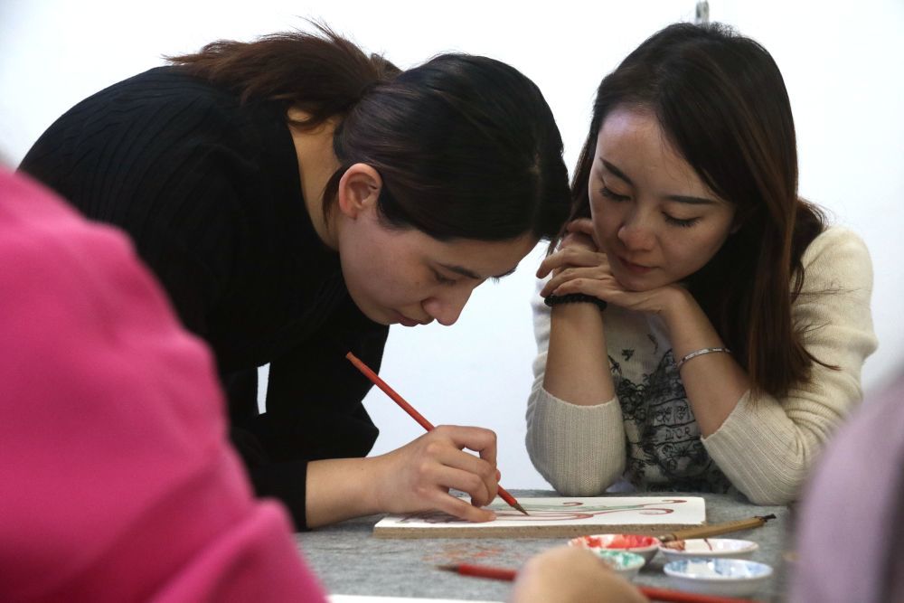 2023年11月29日，在敦煌研究院莫高学堂，研学导师（左）指导学员临摹敦煌壁画。张晓亮　摄