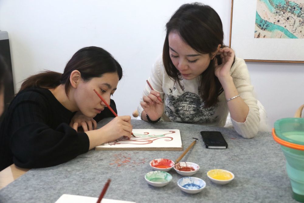 2023年11月29日，在敦煌研究院莫高学堂，研学导师（左）指导学员临摹敦煌壁画。张晓亮　摄