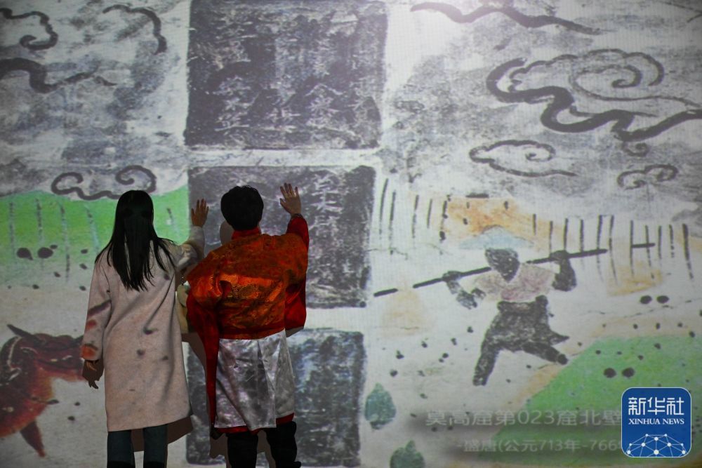 11月28日，在天津数字艺术博物馆，观众通过数字技术与敦煌壁画作品互动。