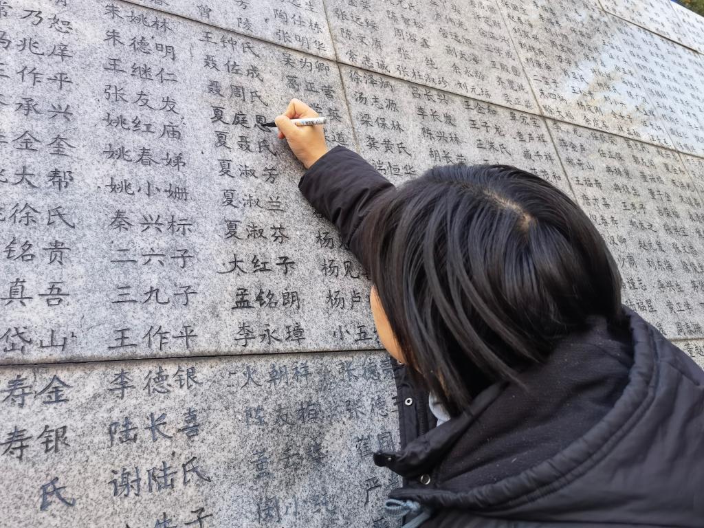 南京大屠杀幸存者夏淑琴的外孙女夏媛为“哭墙”上家人的姓名“描新”。新华社记者邱冰清 摄