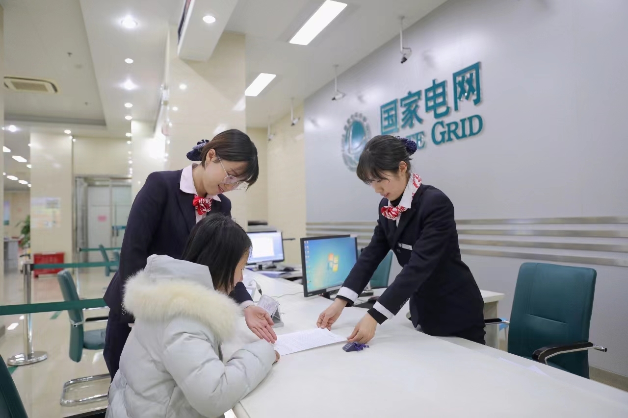 国网石家庄供电公司供电营业厅工作人员为用户办理“过户+改类”业务。（摄影：李兵）