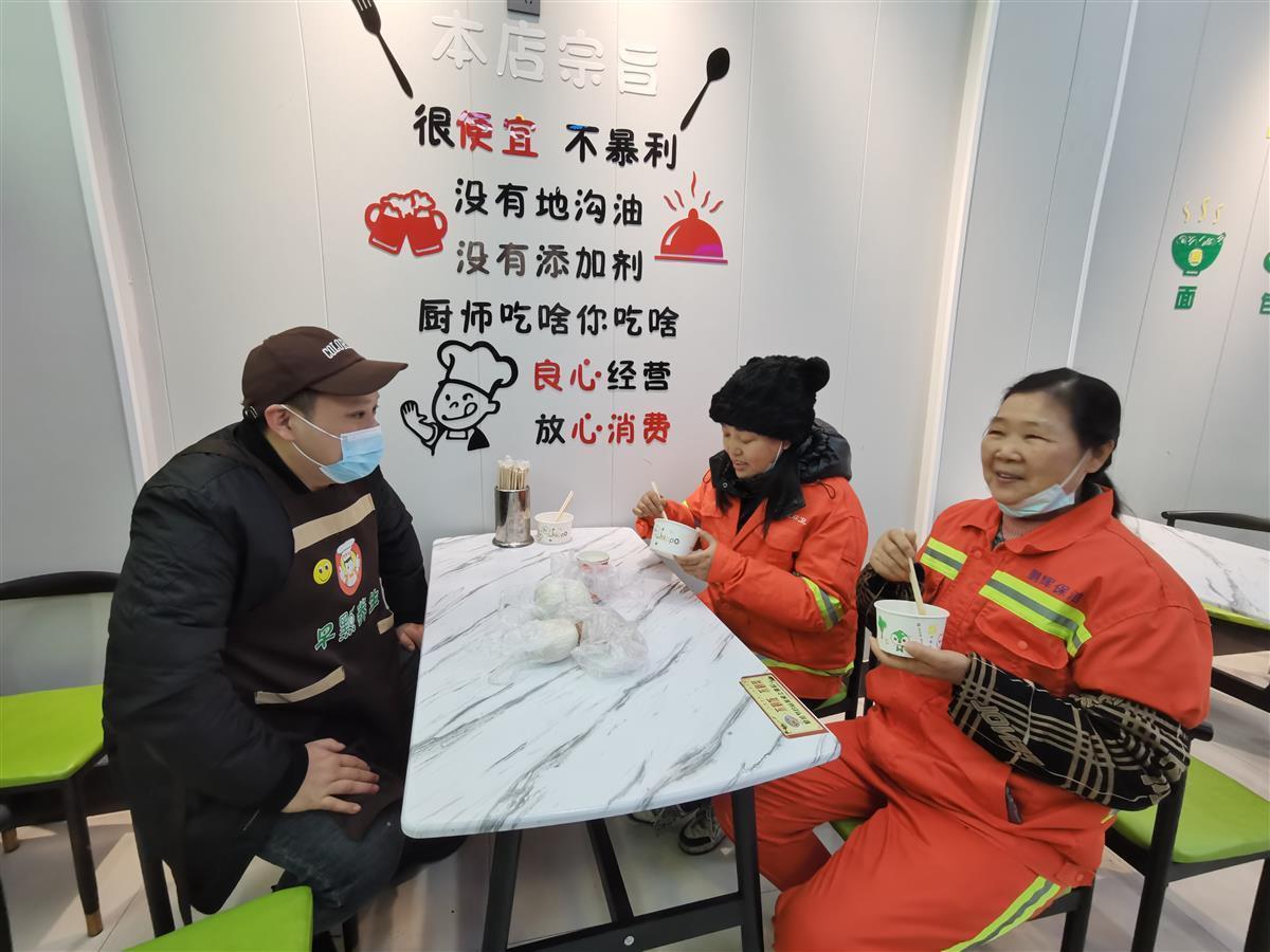 店主雷琼与免费过早的环卫工人交谈