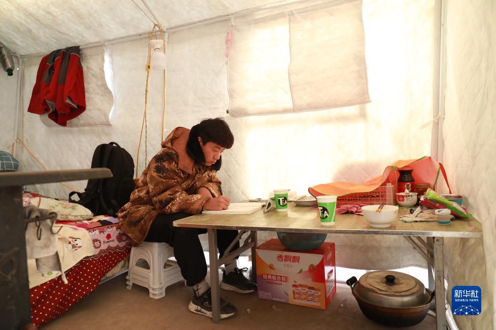 12月22日,积石山县民族中学高二学生秦明贵在村里的临时安置点听课。