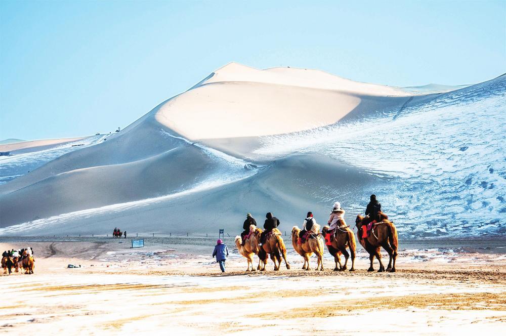 2023年12月16日，雪后初霁，敦煌市旅游景区游客骑骆驼欣赏大漠风光。 新甘肃&middot;甘肃经济日报通讯员　王斌银　摄