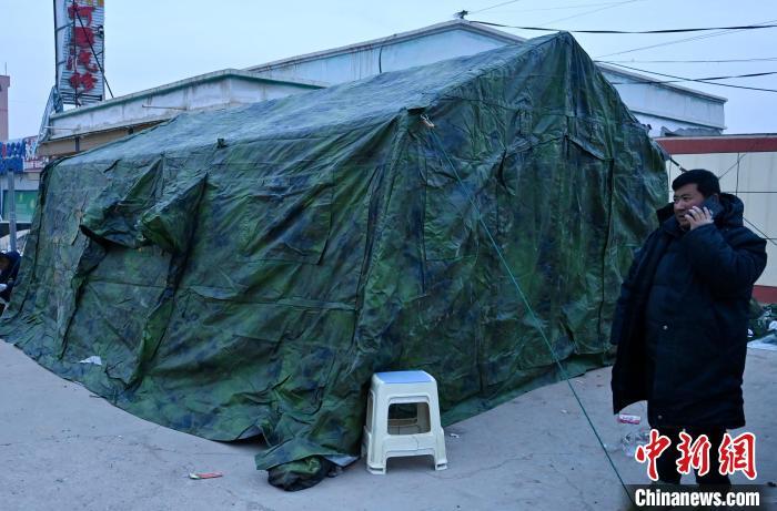 12月20日，马尕主麻一家从路边露天空地处，搬进温暖的帐篷，他站在帐篷前向致电问候的朋友报平安。中新社记者　李亚龙　摄